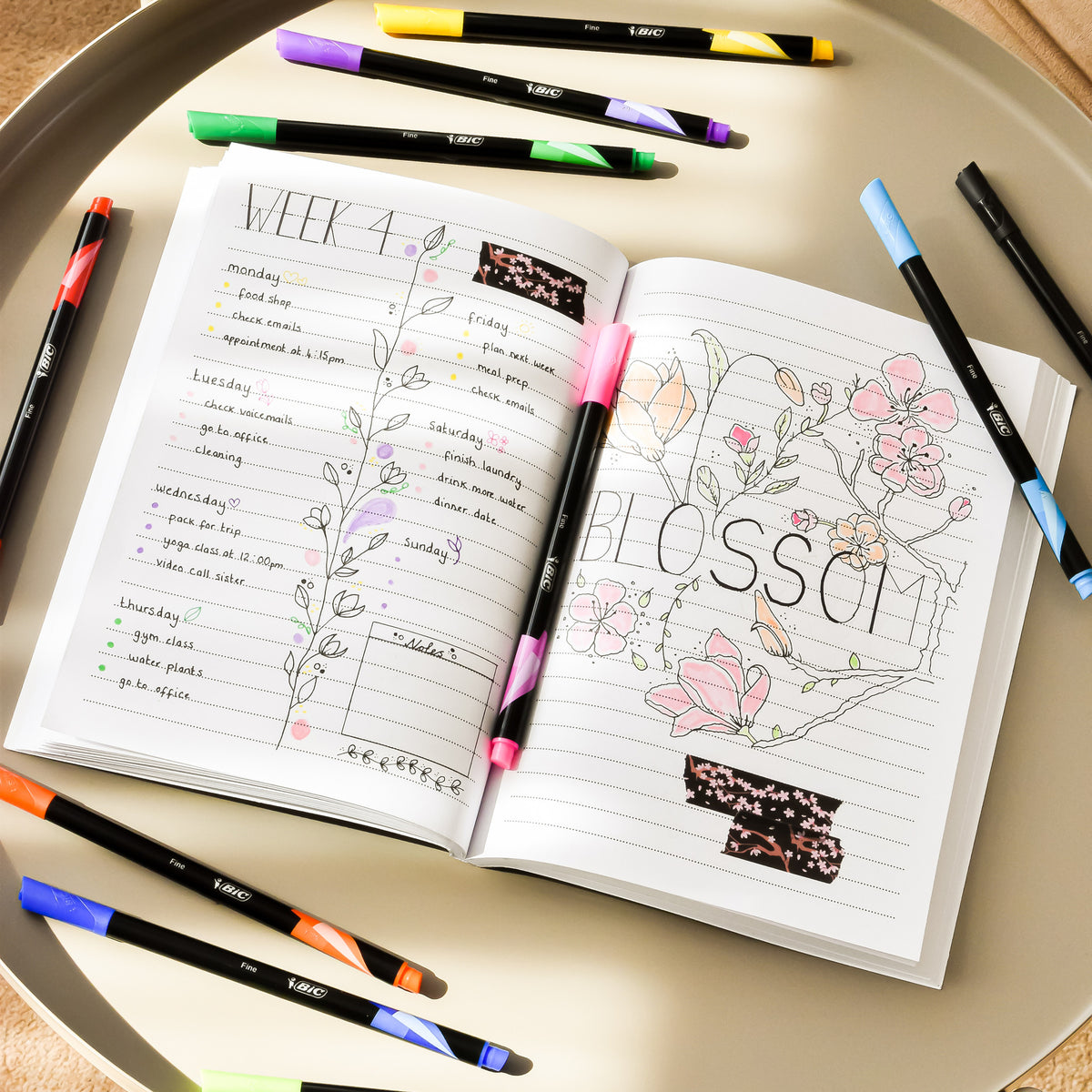 Värikkäitä BIC tusseja sekä muistivihko missä tekstiä ja piirustuksia