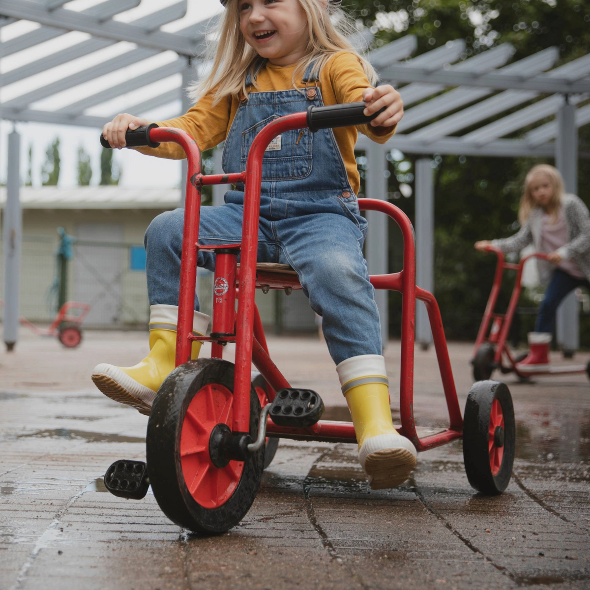 Keltaiset Hai kumisaappaat lapsella joka polkee kolmipyöräisellä